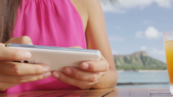 Woman using smart phone device at beach bar playing a game — Stock Video