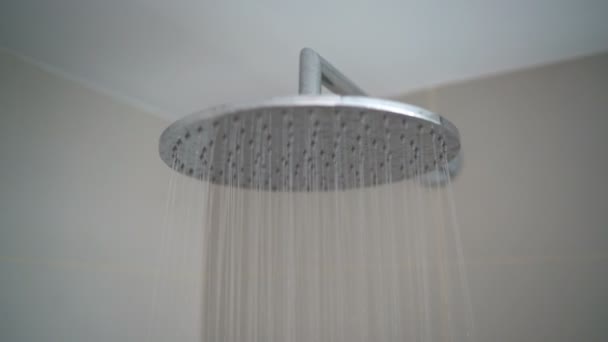 Cabezal de ducha de lluvia primer plano con gotitas de agua corriente en el baño — Vídeo de stock
