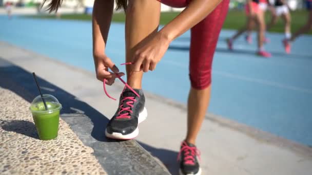 Sportovní běžec se připravuje na běh se zelenou smoothie vázání běžecké boty — Stock video