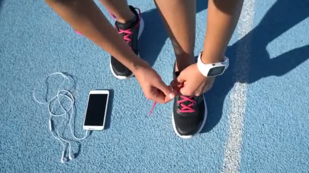 Runner se prépare à attacher des chaussures de course avec écouteurs smartwatch et téléphone — Video
