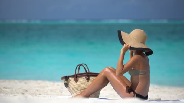 海滩度假妇女在海滩边的腿上涂防晒霜-喷雾瓶 — 图库视频影像
