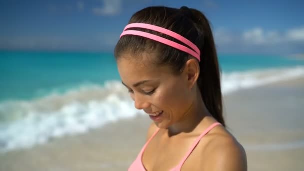 Vrouw luisteren naar muziek lopen oefenen op het strand zetten van telefoons in het oor — Stockvideo