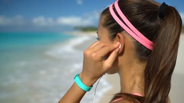 Runner ascolto di musica in esecuzione esercizio sulla spiaggia mettendo Headhones in orecchio — Video Stock