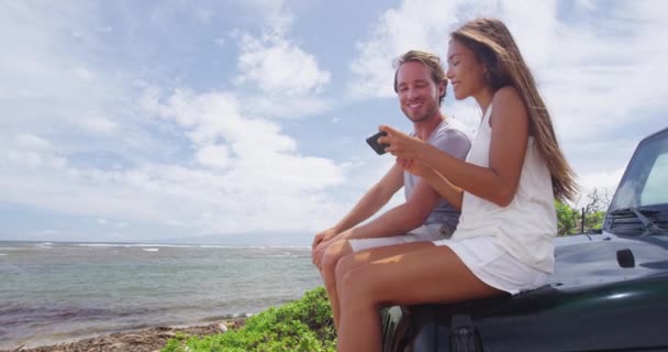 Šťastný pár pomocí Smartphone zatímco sedí na SUV na Shipwreck Beach Hawaii — Stock video