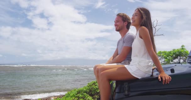 Casal multiétnico feliz que senta-se no tronco do carro do veículo Offroad na praia do naufrágio — Vídeo de Stock