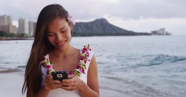 Happy Young Woman In Lei Garland Using Smartphone At Waikiki Beach — стокове відео