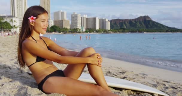 Schöne junge Frau sitzt auf Surfbrett am Strand von Waikiki — Stockvideo