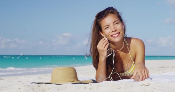 Mujer de vacaciones en la playa con auriculares escuchando música o audiolibro — Vídeo de stock