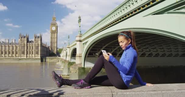 Лондонский бегун по телефону спортивной формы женщина с помощью мобильного смартфона на Big Ben — стоковое видео