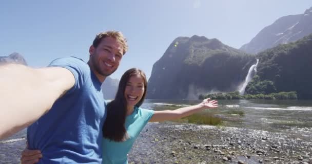 Pareja multicultural tomando selfie video divirtiéndose en Nueva Zelanda Milford Sound — Vídeo de stock