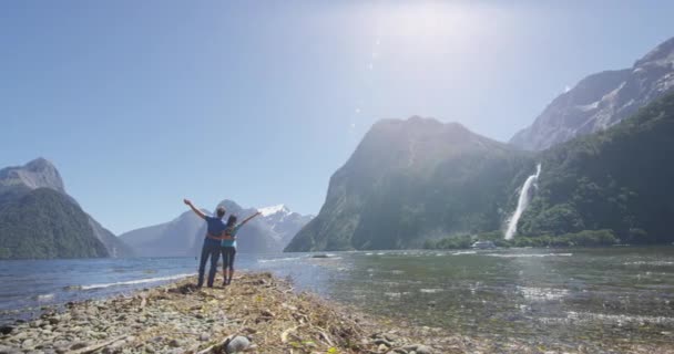 Odkryta para szczęśliwa z ramionami wyciągniętymi w Milford Sound Nowa Zelandia — Wideo stockowe