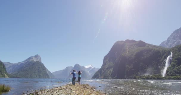 Couple celebrating jumping having fun outdoors in Milford Sound New Zealand — Stock Video