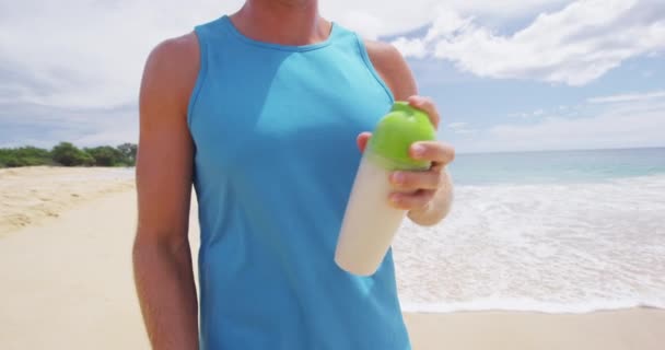Proteinowy napój - człowiek potrząsający butelką sportową z mieszanką protein w proszku poza plażą — Wideo stockowe