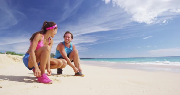 Casal correndo amarrar sapatos cadarços em tênis de corrida na praia — Vídeo de Stock