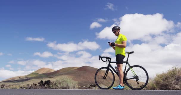 Τηλέφωνο - Ποδηλάτης άνθρωπος ποδηλασία στο ποδήλατο δρόμου χρησιμοποιώντας το smartphone app — Αρχείο Βίντεο