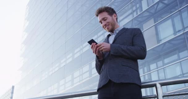 SMS-y człowiek za pomocą aplikacji na smartfonie w dzielnicy biznesowej miasta — Wideo stockowe