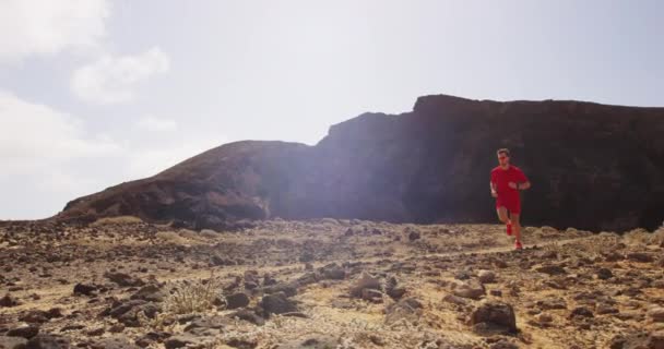 ランニングマン-赤いランニングウェアで速く走る砂漠の道を走る男性ランナー — ストック動画