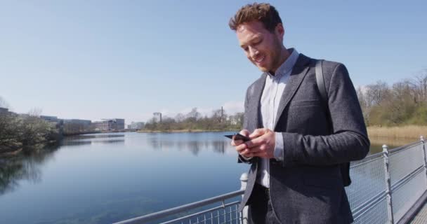 Smartphone - Jonge stedelijke professionele zakenman met behulp van telefoon wandelen in Park — Stockvideo