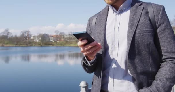 Telefon - Junger urbaner Geschäftsmann läuft mit Smartphone im Park — Stockvideo