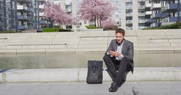 Smartphone - Junger urbaner Geschäftsmann mit Handy entspannt in der Stadt — Stockvideo