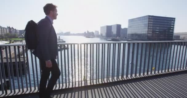 Jonge stedelijke professionele zakenman die naar het werk loopt en rugzak draagt — Stockvideo