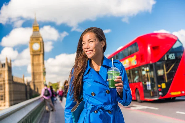 健康的なロンドンの都市のビジネス女性は緑のデトックススムージーを飲みますビッグベン、赤のダブルデッキバスの背景、ロンドンヨーロッパの目的地、イングランド、イギリスとウェストミンスター橋を歩く — ストック写真