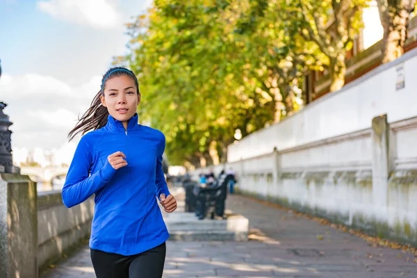 City jogging Asian runner running in London street. Active healthy lifestyle girl doing exercise workout outdoor. Motivation for weight loss, urban life