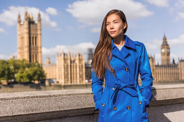 Londres estilo de vida da cidade Mulher de negócios asiática Europa outono viajar em casaco de trincheira azul. Modelo multirracial em moda queda outerwear em Westminster e Big Ben, famoso destino urbano europeu — Fotografia de Stock