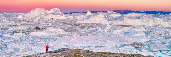 Grönland gezgini turist gün batımında yürüyüşe çıkıyor. Kuzey Buz Denizi 'nde macera gezisi, okyanustaki buzdağlarından yüzen buz. Panorama Panoraması — Stok fotoğraf