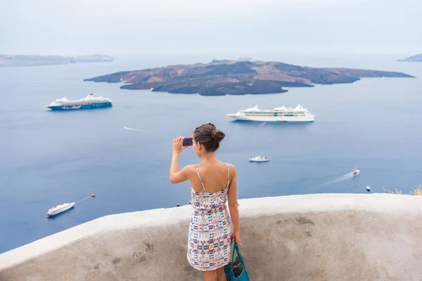 ヨーロッパ旅行観光の女性は、サントリーニ島、オア、ギリシャの地中海の電話で写真を撮ります,海の背景に航海クルーズ船と — ストック写真