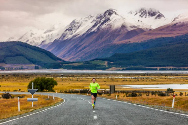 Hombre corredor corriendo corriendo por carretera en el paisaje de montaña en Nueva Zelanda destino de viaje. atleta masculino corredor entrenamiento cardio en frío amanecer mañana ejercicio solo en el fondo de la naturaleza —  Fotos de Stock