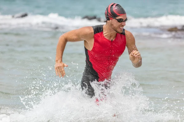 Pływak z Triatlonu. Mężczyzna triatlonista pływak biegnący z oceanu wykończenie wyścig pływacki. Fit man kończący pływanie sprinting określony z wody w profesjonalnym triathlon garnitur szkolenia dla Iron Man — Zdjęcie stockowe