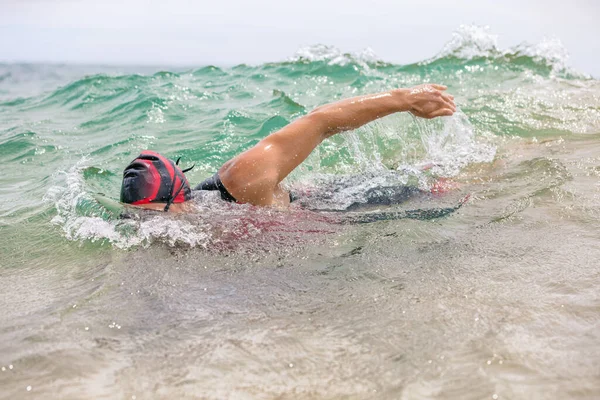 Yüzücü triatlon yüzme yarışı sırasında okyanus dalgalarında serbest yüzer. Deniz suyunda yüzen bir triatlet. Profesyonel triatlon kıyafetli bir erkek triatloncu. — Stok fotoğraf