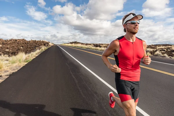 O corredor se encaixa atleta homem correndo em triatlo terno treinamento para o Homem de Ferro no Havaí. Ajuste triatleta masculino exercitando resistência cardio na estrada — Fotografia de Stock