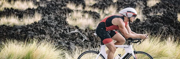 Biking triathlete man cycling road bike under the rain during triathlon race in Hawaii nature landscape. Sport athlete training endurance workout extreme weather banner panoramic — Stock Photo, Image