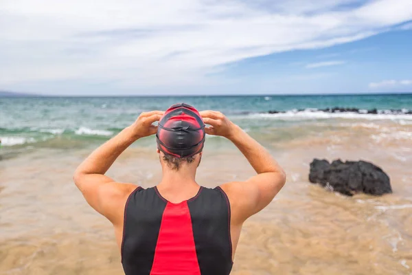 Triathlonschwimmer beim Schwimmen bereit zum Schwimmen mit Blick auf den Horizont des Ozeans. Triathlet Schwimmer setzt Schwimmbrille für den Wettkampf auf. Profi-Athlet im Triathlonanzug trainiert für Ironman auf Hawaii — Stockfoto