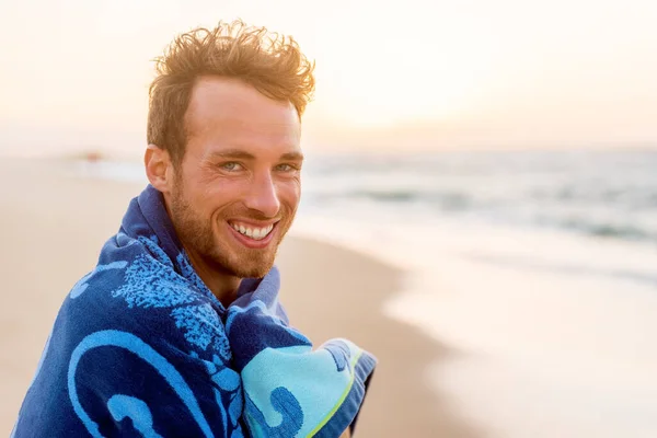 Sonriente joven guapo retrato de belleza en la playa al atardecer mirando a la cámara riendo, sonrisa saludable cara de modelo feliz en toalla. —  Fotos de Stock