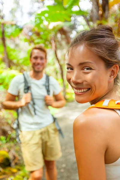 Senderismo mochileros turistas viajes al aire libre estilo de vida jóvenes caminando en el bosque en el sendero sonriendo feliz.Dos adultos pareja en aventura de vacaciones. Mujer asiática con mochila en vacaciones de verano. — Foto de Stock