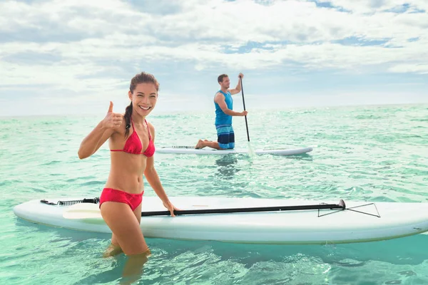 Paddleboard beach people on stand-up paddle boards surf in ocean on Hawaii beach (en inglés). Mezcla de raza pareja mujer y caucásico hombre disfrutando de watersport —  Fotos de Stock