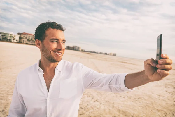 Selfie vacation beach man in white linen shirt taking photo with mobile phone on honeymoon travel vacation. Happy young using smartphone on holdiay — Stock Photo, Image