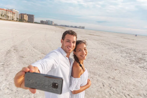 Selfie férias praia casal romântico lua de mel. Jovem feliz e homem tirando foto com telefone recém-casados em Holdiay — Fotografia de Stock