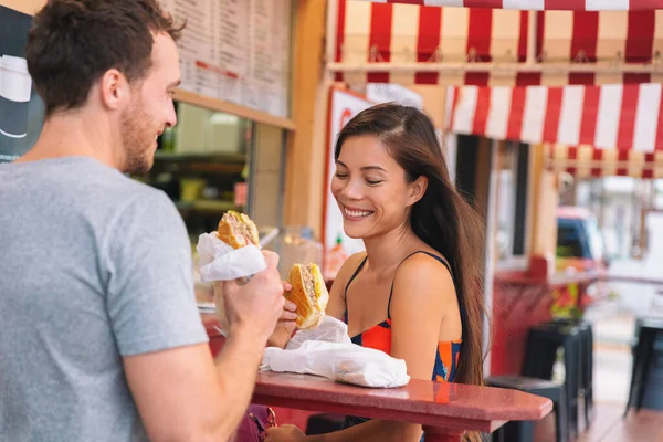 Glada par äter smörgåsar på typiskt retrocafé i Florida. Kuba smörgås lokal mat. Sommar resor turist livsstil ung asiatisk kvinna ler äta lunch utanför — Stockfoto