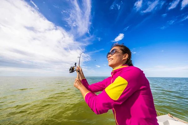 Vissen vrouw hebben plezier leren vissen werpen lijn op de oceaan. Toeristen op boottocht — Stockfoto