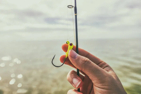 Fishing hook closeup watersport gear. Woman hand holding line