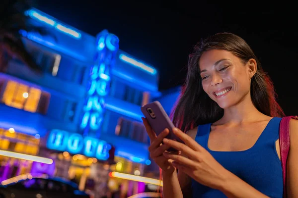 Miami woman sms 't telefoon lopen op Ocean drive South Beach FLORIDA, USA. Art Deco hotels en restaurants 's nachts wereldberoemde toeristische bestemming voor het nachtleven. Smartphone reizen bijna levensstijl — Stockfoto