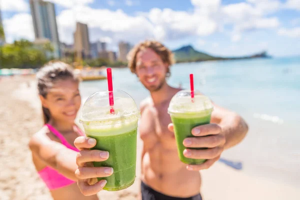 Spor salonu çifti sahilde yeşil smoothie içiyor. — Stok fotoğraf