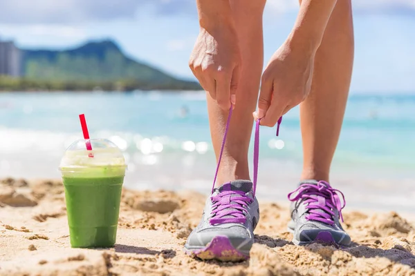 Grüne Smoothie-Fitness-Frau bindet Laufschuhe — Stockfoto