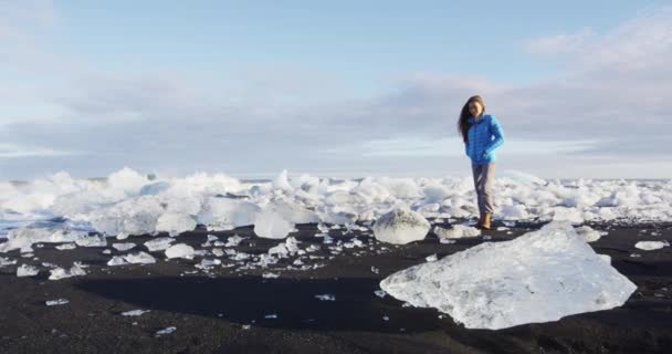 Исландская природа на Алмазном пляже со льдом - женщина-туристка, гуляющая пешком — стоковое видео