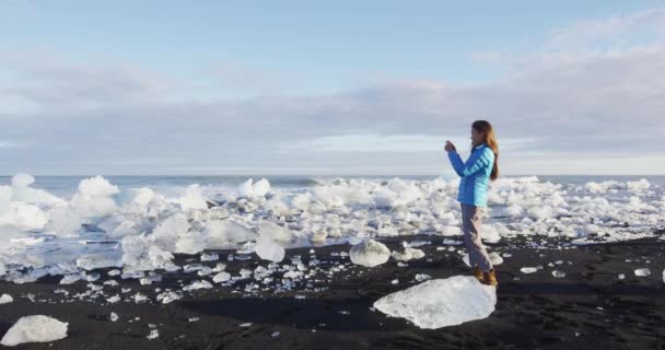 Iceland nature at Diamond beach with ice - Woman tourist taking photograph — Stock Video