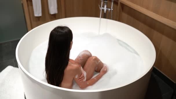 Ванна. Женщина купается в ванне наслаждаясь расслабляющей ванны образ жизни реальный естественный уход за телом расслабляющий спокойный и спокойный — стоковое видео
